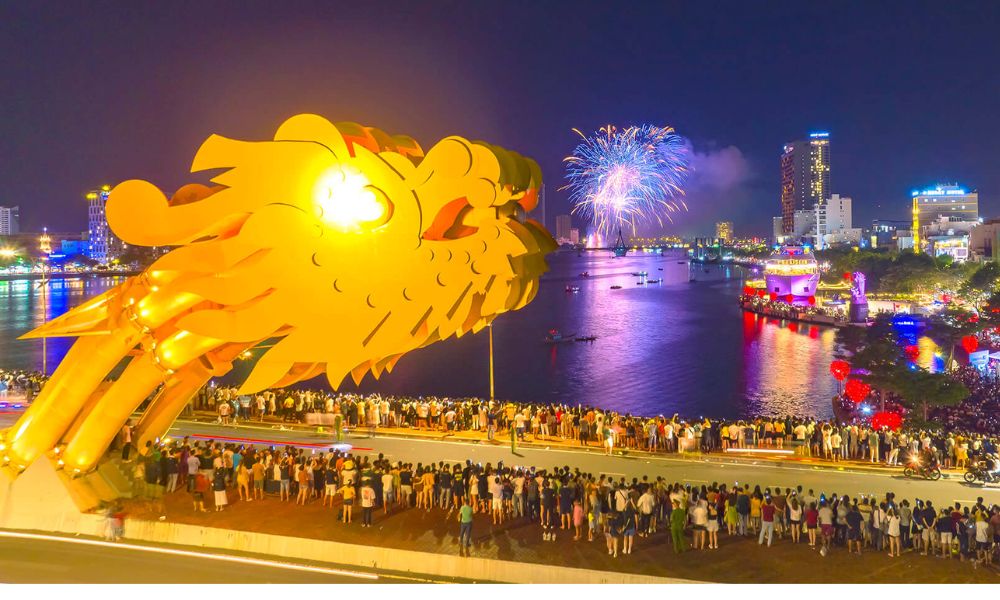 Cầu Rồng và đông đảo khán giả chiêm ngưỡng lễ hội pháo hoa Đà Nẵng rực rỡ phản chiếu trên sông Hàn về đêm